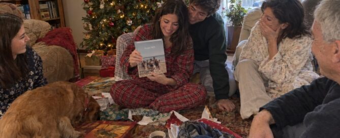 idée cadeau Noël original : famille qui ouvre un livre de sa conversation WhatsApp au pied du sapin
